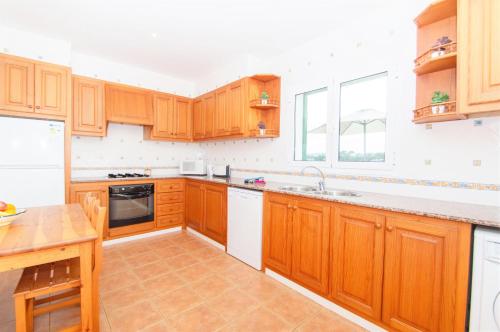 a large kitchen with wooden cabinets and a table at Villa Mirador B by Sonne Villas in Cala Galdana