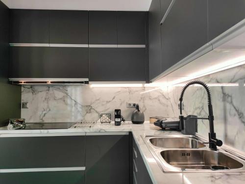 a kitchen with black cabinets and a sink at Meteora Scenic Loft in Kalabaka