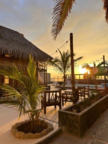 un complejo con mesas, palmeras y puestas de sol en Hotel Puerto Antiguo, en Los Órganos