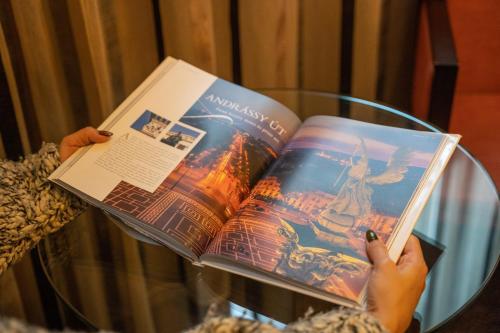 a person reading a book on a glass table at Mamaison Hotel Andrassy Budapest in Budapest