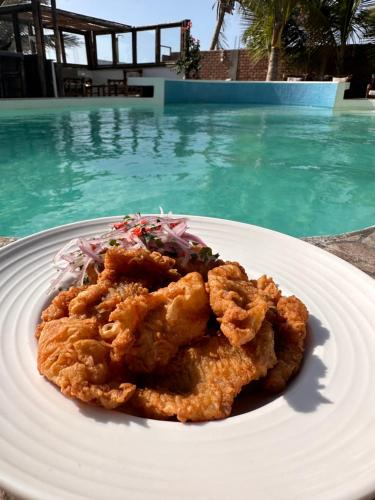 a plate of food on a table next to a swimming pool at Hotel Puerto Antiguo in Los Órganos