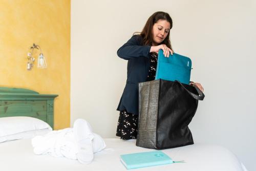 a woman is holding a bag on a bed at Hotel Residence Montelago in Ternate