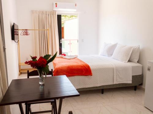 a bedroom with a bed with a table and a window at Residencial Santa Fé in Trancoso