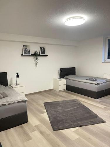 a white room with two beds and a rug at Monteurwohnung Kassel, 4 Personen in Niestetal