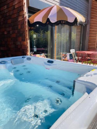 un bain à remous avec un parasol dans la cour dans l'établissement La régate avec jaccuzi à 50 m du centre historique, à Sarlat-la-Canéda