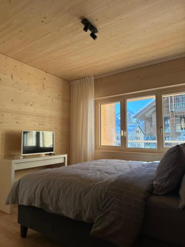 a bedroom with a bed and a flat screen tv at Mondholz Ferienwohnung in Andermatt