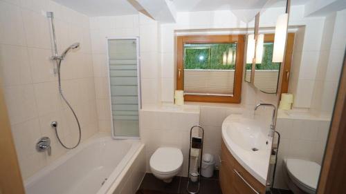 y baño con bañera, aseo y lavamanos. en Ferienwohnung SEPP en Mayrhofen