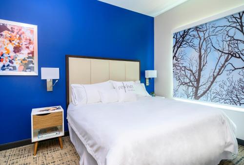 a bedroom with a large bed with blue walls at Revisn in Raleigh