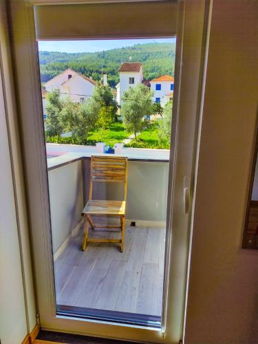 a chair sitting on a balcony looking out a window at Casa de Campo Vale do Ceira in Góis