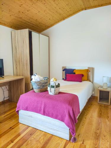 a bedroom with a bed with two baskets on it at Casa de Campo Vale do Ceira in Góis