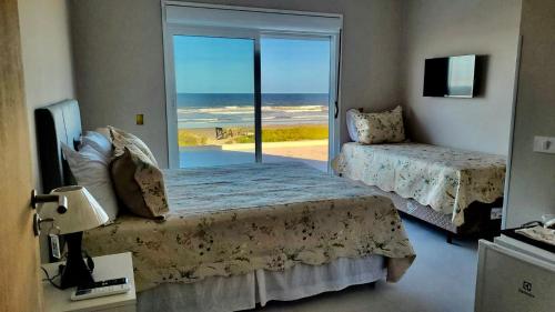 a bedroom with two beds and a view of the ocean at Pousada Recanto Vô Fredo in Guaratuba