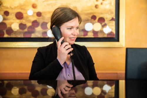 a woman talking on a phone while sitting at a table at Hotel Residence Montelago in Ternate