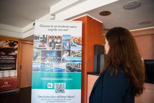 a woman standing next to a sign in a room at Hotel Residence Montelago in Ternate
