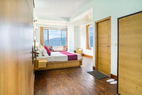 um quarto com uma cama e uma grande janela em Hotel Blue Poppy em Gangtok
