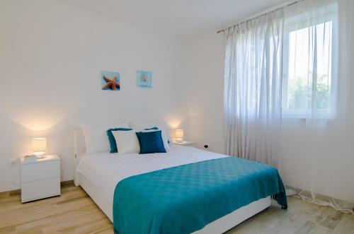a bedroom with a large bed with blue sheets and a window at Studio apartment Stella in Labin