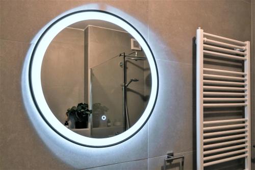 a round mirror on a wall in a bathroom at Špansko view -Comfy apartment in Zagreb