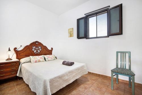 a bedroom with a bed and a chair and a window at Apartamento la Solapa in Pájara