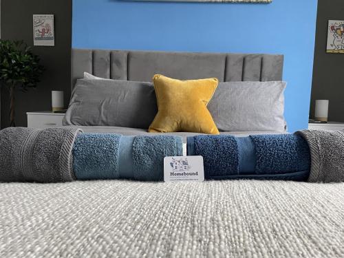 a bed with blue and gray pillows on it at Coastal Comfort, Seaside Flat in Margate