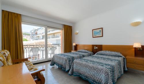 a hotel room with two beds and a balcony at Apartamentos Leonor Carihuela in Torremolinos