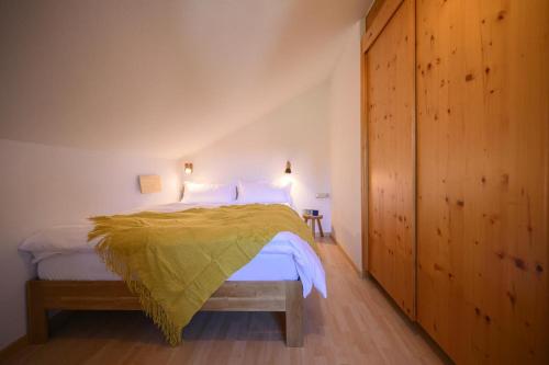 ein Schlafzimmer mit einem Bett mit einer gelben Decke darauf in der Unterkunft Ferienwohnung Lampl 7 in Bad Kohlgrub