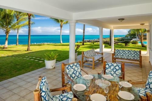 un patio con mesa, sillas y el océano en Luxury Oceanfront Villa with Amazing Views, en Sosúa
