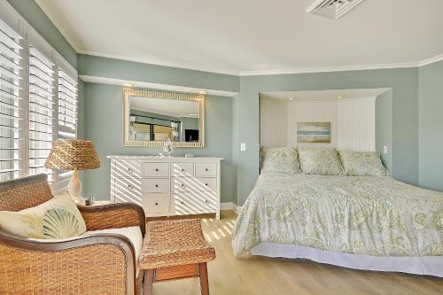 ein Schlafzimmer mit einem Bett, einem Stuhl und einem Spiegel in der Unterkunft 202E Port O'Call in Isle of Palms