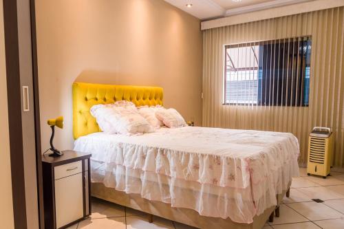 1 dormitorio con 1 cama grande y cabecero amarillo en Apto 15 min das Aguas Termais em Araxa MG, en Araxá