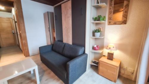 a living room with a blue chair and a table at Studio Panorama - Vue montagne et village, Centre la Clusaz - AravisTour in La Clusaz