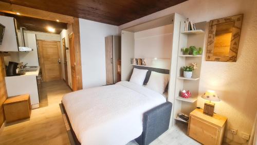 ein kleines Schlafzimmer mit einem weißen Bett und Regalen in der Unterkunft Studio Panorama - Vue montagne et village, Centre la Clusaz - AravisTour in La Clusaz