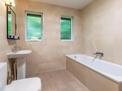 a bathroom with a tub and a sink and a toilet at 2 Bed in St. Mellion 87714 in St. Mellion