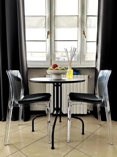 a table with two chairs and a bowl of fruit on it at Il Bumbunin Esclusivo monolocale nel cuore di Asti in Asti