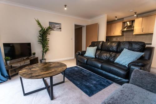 a living room with a leather couch and a table at April Disc - Long Stay - Contractors in Bristol
