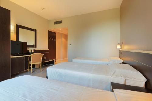 a hotel room with two beds and a desk at Hotel Ristorante Al Mulino by LVG Hotel Collection in Alessandria