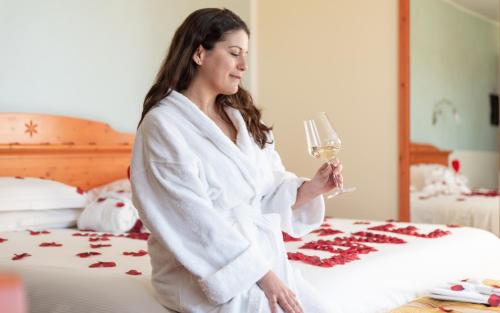 a woman in a bathrobe holding a glass of wine at Hotel Residence Montelago in Ternate