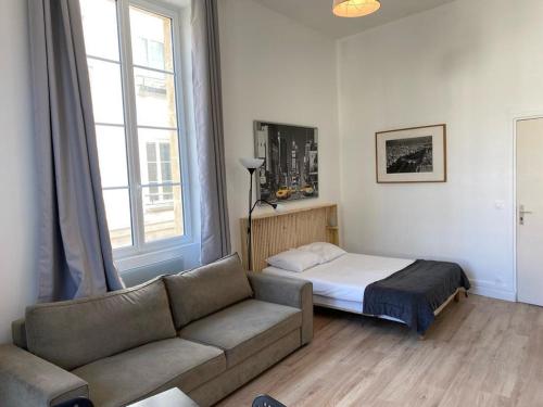 un soggiorno con divano e letto di Studio Grands Boulevards a Parigi