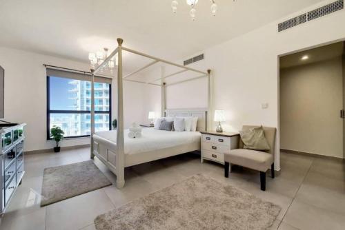 ドバイにあるJbr Sea View Captivating 4-Bed Apartment in Dubaiの白いベッドルーム(天蓋付きベッド1台、椅子付)