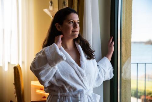 a woman in a towel looking out a window at Hotel Residence Montelago in Ternate