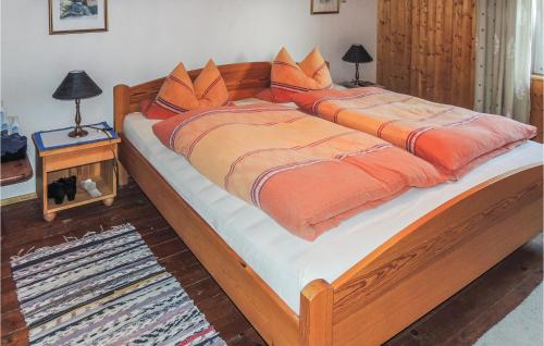 Cama grande de madera con edredón y almohadas de color naranja en Ferienhaus In Weissenstein en Fresach