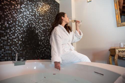 a woman sitting in a bath tub drinking from a bottle at Hotel Residence Montelago in Ternate