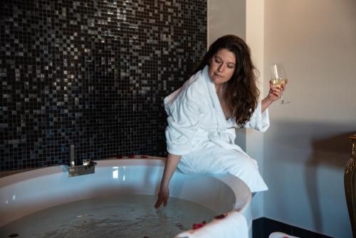 a woman in a bath tub holding a glass of wine at Hotel Residence Montelago in Ternate