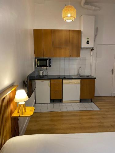 a kitchen with wooden cabinets and a table with a lamp at Studio Bonne Nouvelle in Paris