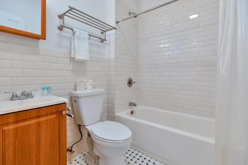 a white bathroom with a toilet and a bath tub at Urban 1BR Close to PATH Train 15min to NYC in Hoboken