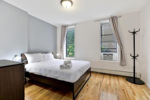 a white bedroom with a bed and a window at Urban 1BR Close to PATH Train 15min to NYC in Hoboken