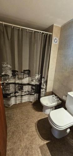 Un baño con inodoro y cortina de ducha. en 8 Depto de un dormitorio cochera, en Rosario
