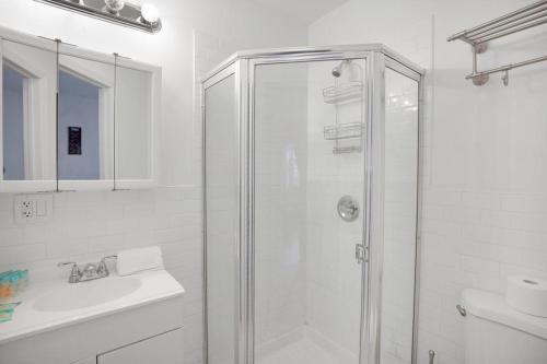 a white bathroom with a shower and a sink at Central and Great Location 1BR 15min to NYC in Hoboken