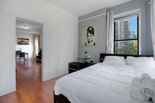 um quarto com uma cama branca e uma grande janela em Central and Great Location 1BR 15min to NYC em Hoboken