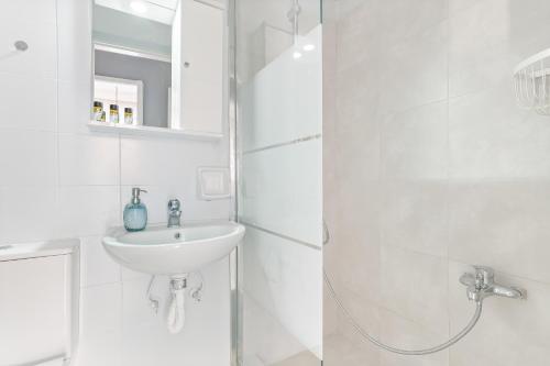 ein weißes Bad mit einem Waschbecken und einer Dusche in der Unterkunft Thanasis Family Apartment in Athen