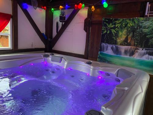 una vasca idromassaggio con luci viola in una stanza di gîte en pierre le paradis parc clôturé spa jacuzzi 5 places piscine au Périgord pourpre 9km de bergerac a Saint-Aubin-de-Lanquais