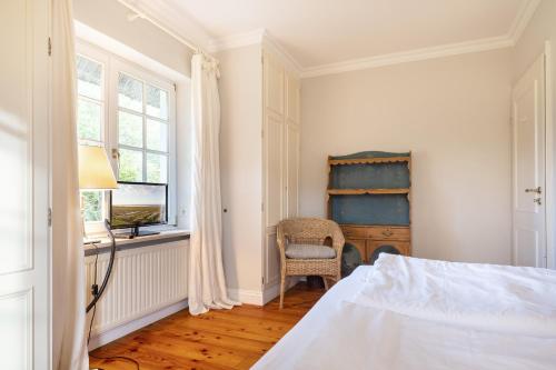 a bedroom with a bed and a desk and a window at Sylthause in Archsum