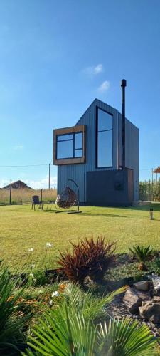 a tiny house on a grassy field with a dog at Tiny House Cambará in Cambara do Sul